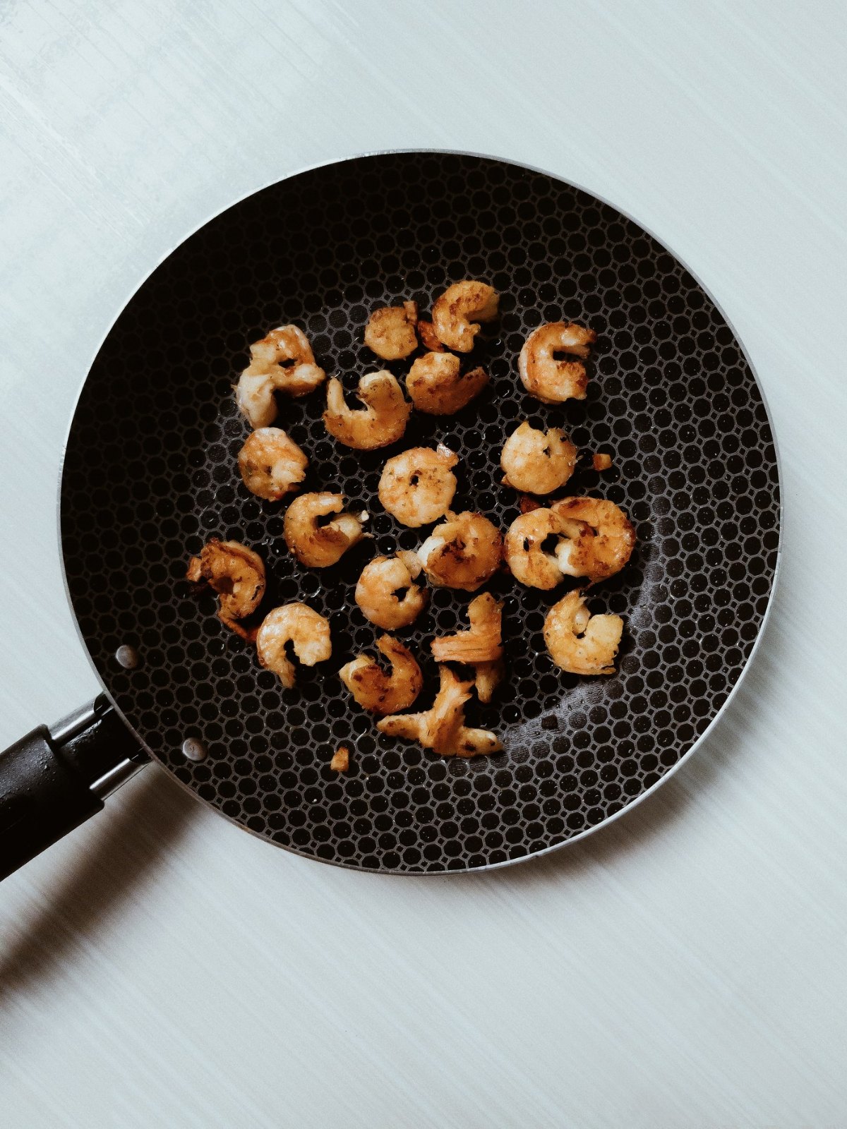 Shrimp seared in a black pan, pink outside