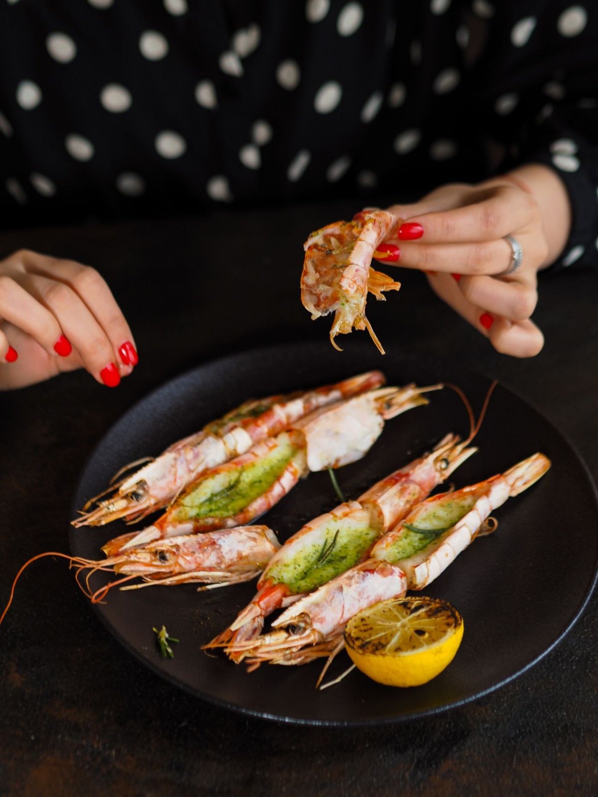Grilled shrimp served with lemon on a black plate