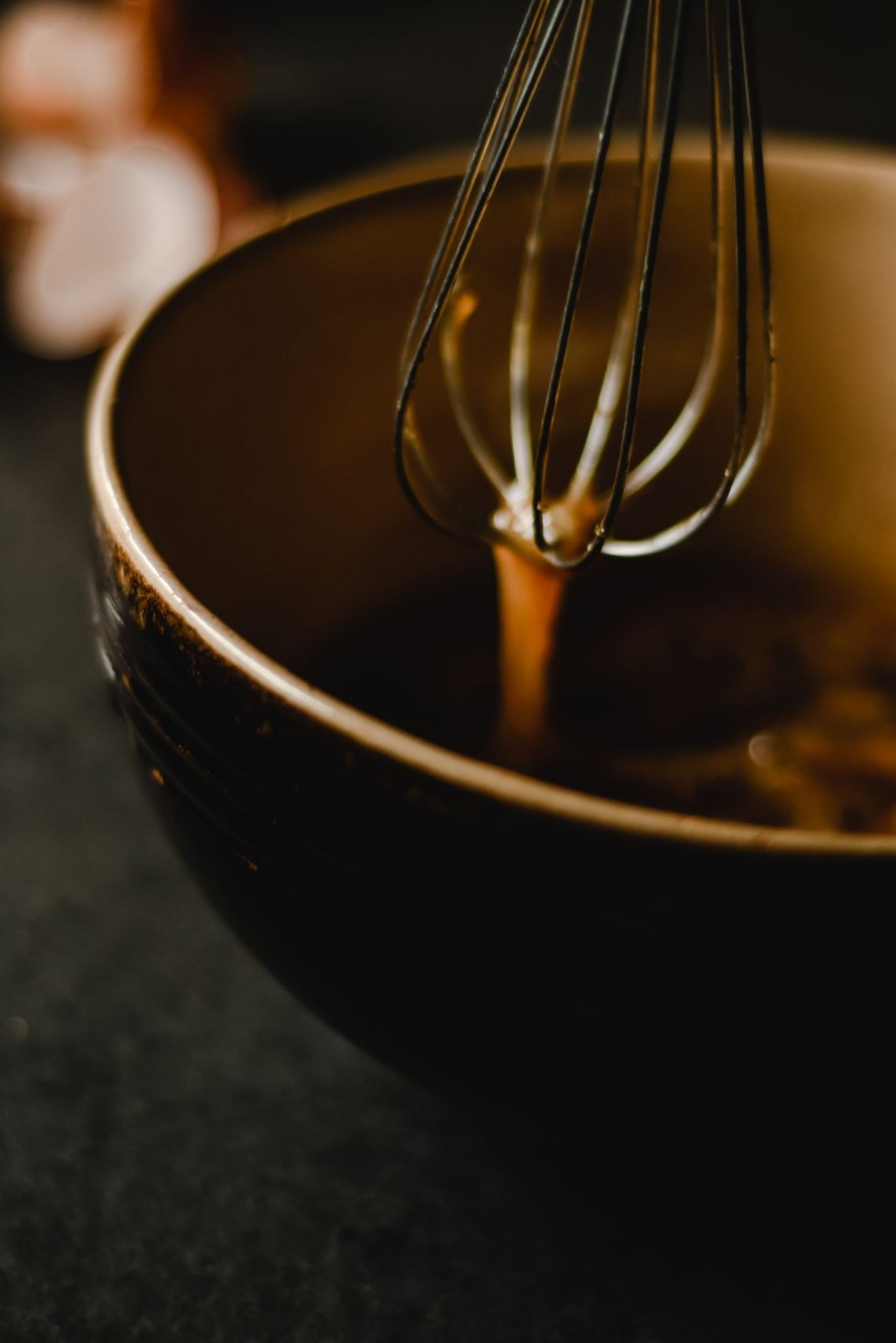 Egg yolks on a whisk over a mixing bowl